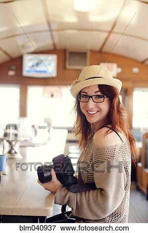 Caucasian woman holding camera in restaurant View Large Photo Image Stock Photo - Caucasian woman holding camera in restaurant. Fotosearch