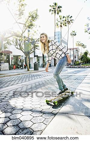 Stock Photography - Caucasian woman riding skateboard. Fotosearch