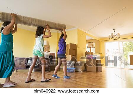Stock Image - Children carrying carpet in new house. Fotosearch