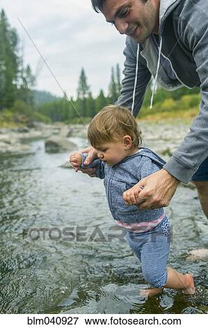 Father helping daughter walk in river View Large Photo Image Stock Photo - Father helping daughter walk in river. Fotosearch