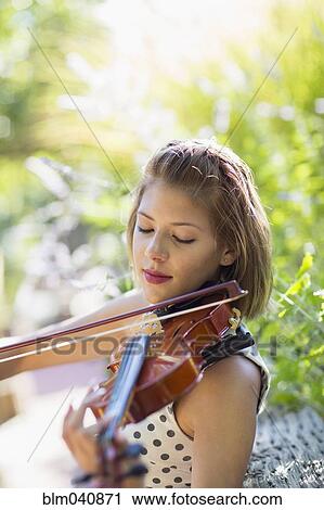 Stock Image - Mixed race musician playing violin outdoors. Fotosearch