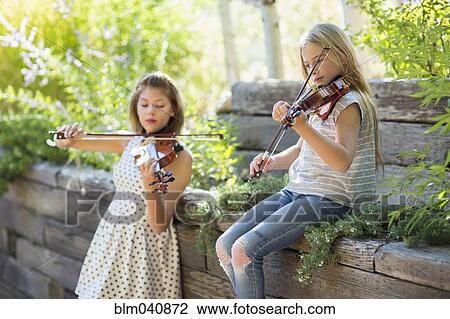 Stock Image - Musicians playing violins outdoors. Fotosearch