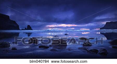 Picture - Rocks on beach under storm clouds. Fotosearch