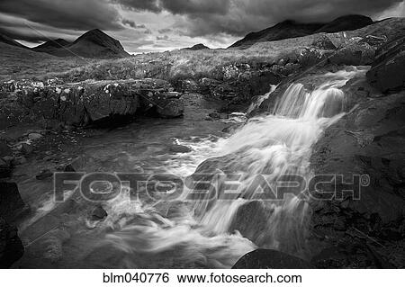 Stock Photograph - Waterfall over rocks in rural landscape. Fotosearch