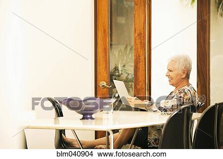 Picture - Woman using digital tablet at table. Fotosearch
