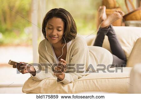 Stock Photo - African American woman listening to earbuds. Fotosearch