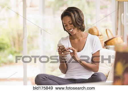 Stock Photo - African American woman using cell phone. Fotosearch