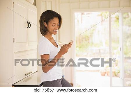 Stock Photo - African American woman using cell phone indoors. Fotosearch