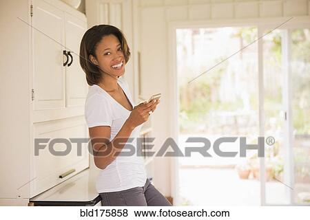 Stock Photo - African American woman using cell phone indoors. Fotosearch