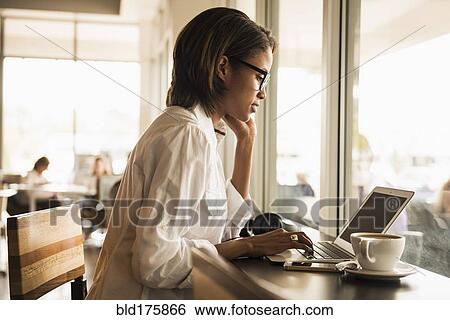 Stock Photograph - African American woman using laptop in cafe. Fotosearch