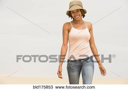 Stock Image - African American woman walking on beach. Fotosearch