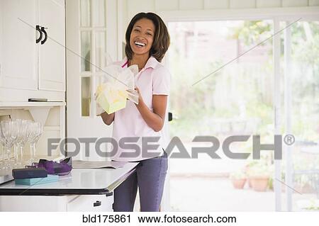 Stock Image - African American woman wrapping gift. Fotosearch