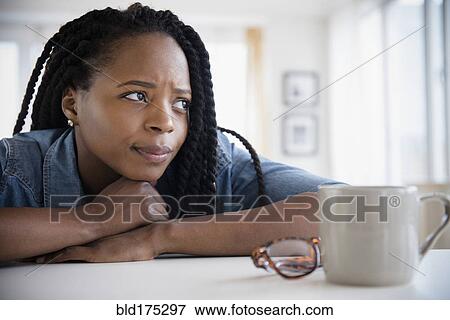Stock Photo - Anxious Black woman resting chin on hands. Fotosearch