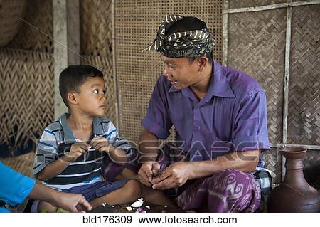Stock Photo - Asian father and son peeling garlic in living room. Fotosearch