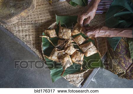 Stock Photo - Asian man knotting woven packages on floor. Fotosearch