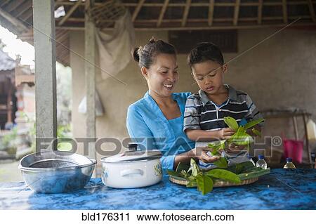 Stock Image - Asian mother and son cooking in outdoor kitchen. Fotosearch