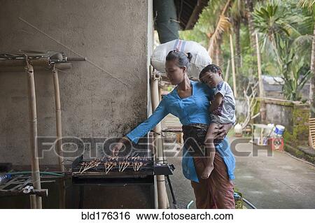 Stock Photograph - Asian mother and son cooking on grill outdoors. Fotosearch