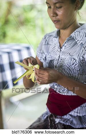 Stock Photograph - Asian woman knotting leaves outdoors. Fotosearch