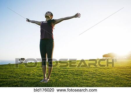 Stock Image - Asian woman standing with arms outstretched. Fotosearch