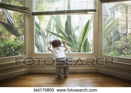 Stock Photography - Baby boy looking out window. Fotosearch