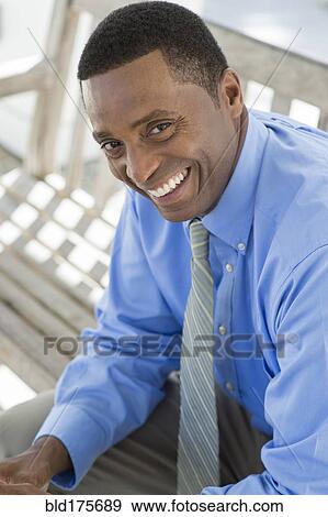 Stock Photo - Black businessman smiling on bench. Fotosearch