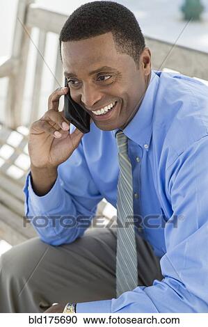 Stock Image - Black businessman talking on cell phone. Fotosearch