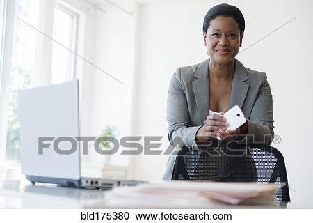 Stock Image - Black businesswoman holding cell phone. Fotosearch