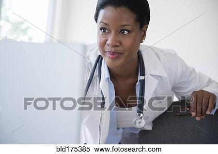 Stock Photography - Black doctor using laptop in office. Fotosearch