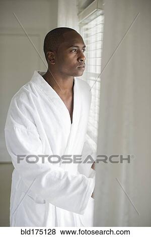 Stock Photo - Black man in bathrobe looking out window. Fotosearch