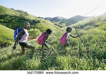 Picture - Black mother and daughters walking on rural hillside. Fotosearch