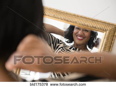 Stock Photo - Black woman admiring herself in mirror. Fotosearch