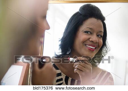 Black woman applying lipstick in mirror View Large Photo Image Stock Photograph - Black woman applying lipstick in mirror. Fotosearch
