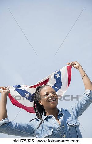 Stock Photography - Black woman carrying American flag banner. Fotosearch