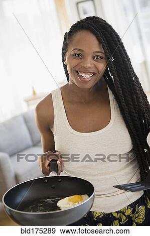 Stock Photo - Black woman cooking egg. Fotosearch