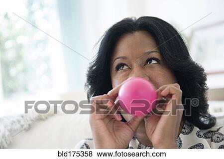 Stock Photo - Black woman inflating balloon. Fotosearch