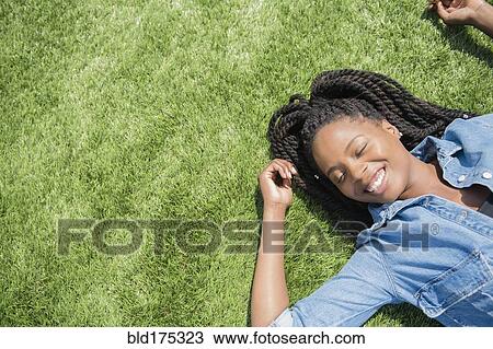 Stock Image - Black woman laying in grass. Fotosearch