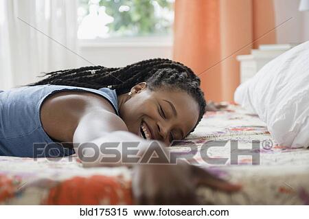 Stock Photography - Black woman laying on bed. Fotosearch