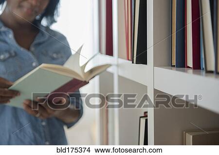 Black woman reading book at bookcase View Large Photo Image Picture - Black woman reading book at bookcase. Fotosearch
