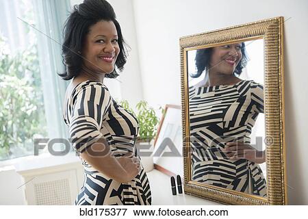 Stock Photo - Black woman smiling near mirror. Fotosearch