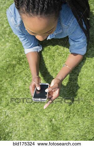 Black woman using cell phone in grass View Large Photo Image Picture - Black woman using cell phone in grass. Fotosearch