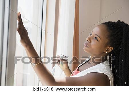 Stock Photo - Black woman washing window. Fotosearch