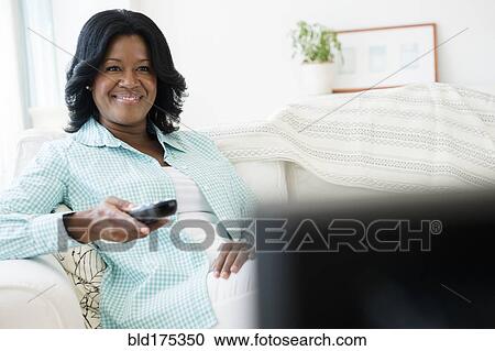 Stock Image - Black woman watching television. Fotosearch