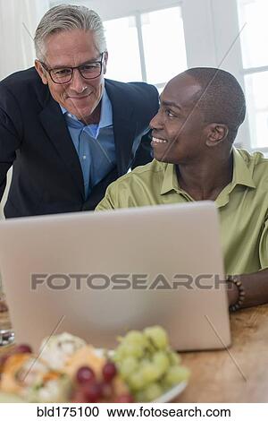 Businessmen using laptop at desk View Large Photo Image Stock Image - Businessmen using laptop at desk. Fotosearch