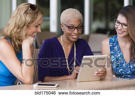 Stock Photograph - Businesswomen using digital tablet at table. Fotosearch