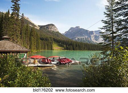 Stock Image - Canoes on wooden dock in rural lake. Fotosearch