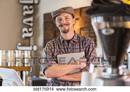 Picture - Caucasian barista holding digital tablet in cafe. Fotosearch