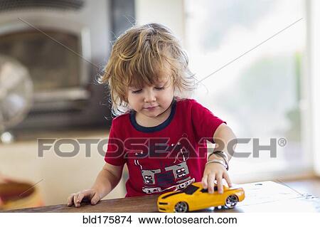 Picture - Caucasian boy playing with toy car. Fotosearch