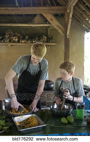 Stock Image - Caucasian brothers cooking in outdoor kitchen. Fotosearch