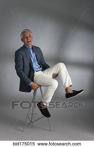 Stock Photography - Caucasian businessman laughing on stool. Fotosearch