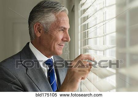 Stock Photography - Caucasian businessman looking out window. Fotosearch